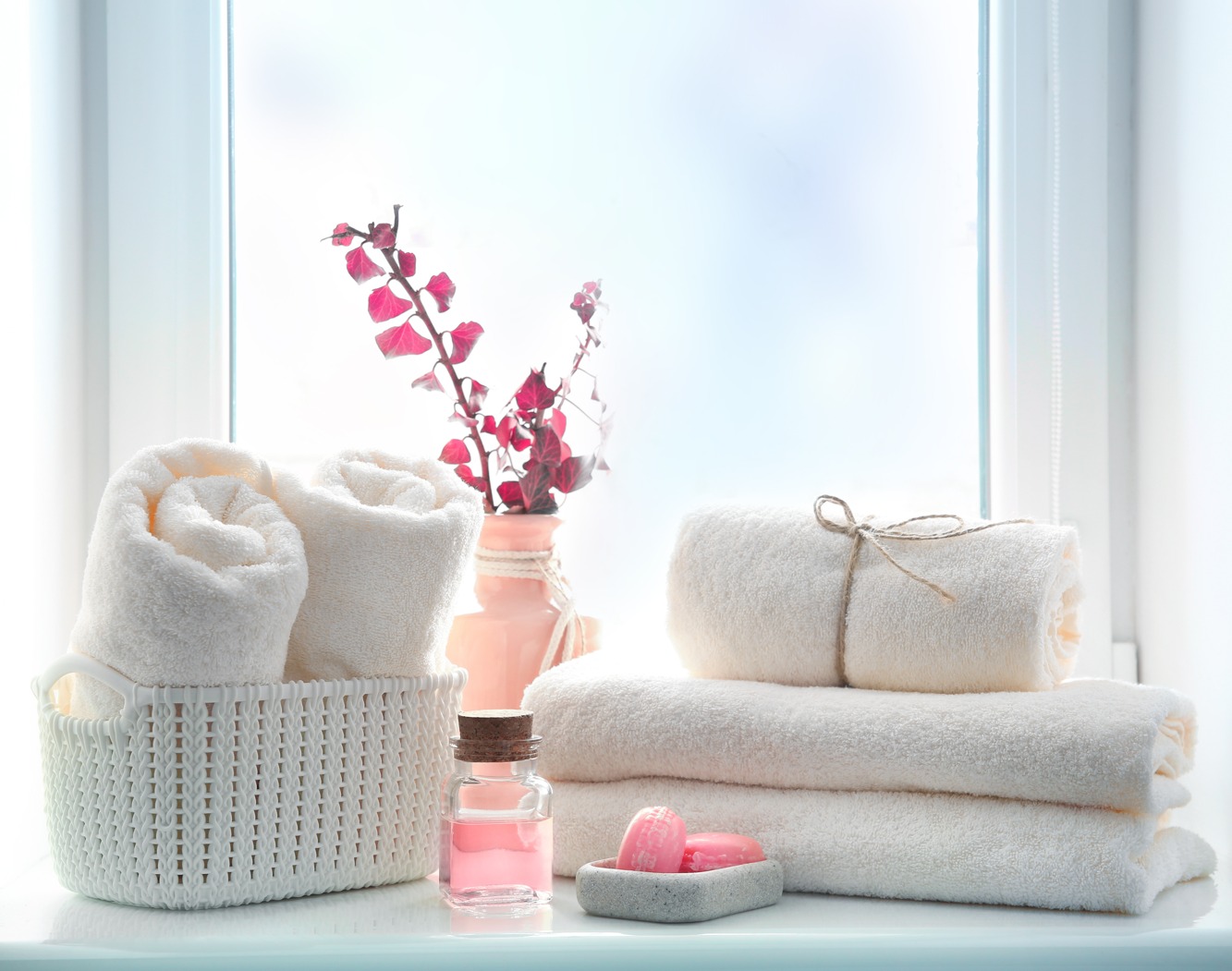 a set of towels with pink decorations such as candles soap and a vase around them