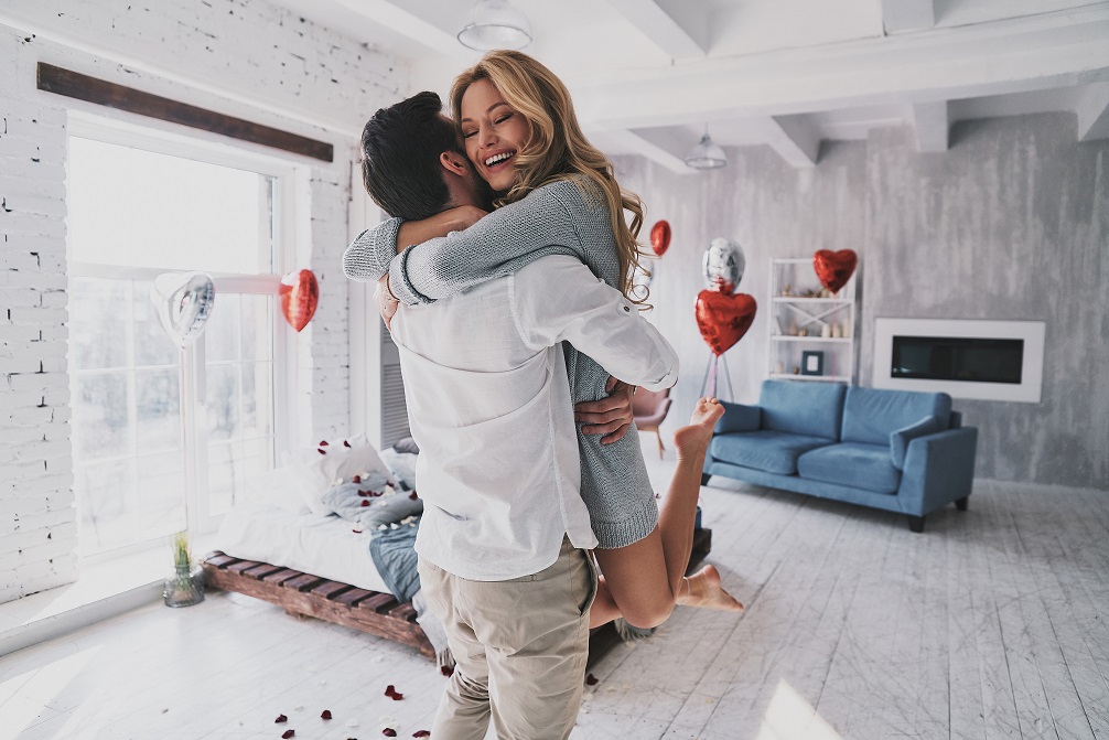 a couple hugging after saying yes to a porposal in their living room