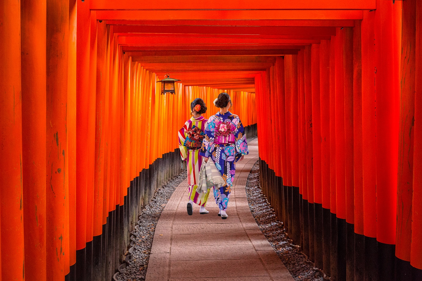 two women in kimonos walking under a traditional japanese structure